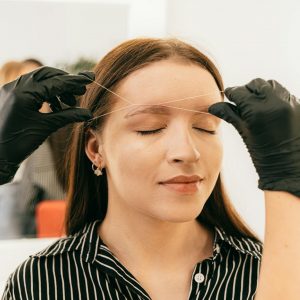 Eyebrow threading in a modern salon setting.