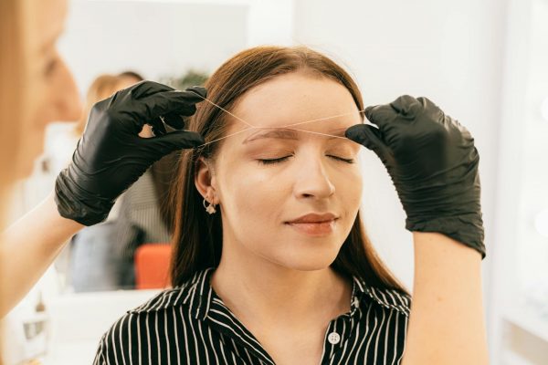 Eyebrow threading in a modern salon setting.